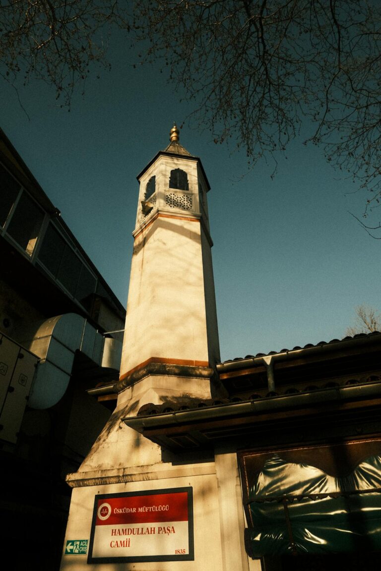 A serene view of the Hamdullah Paşa Mosque minaret in İstanbul, Türkiye, bathed in warm sunlight.