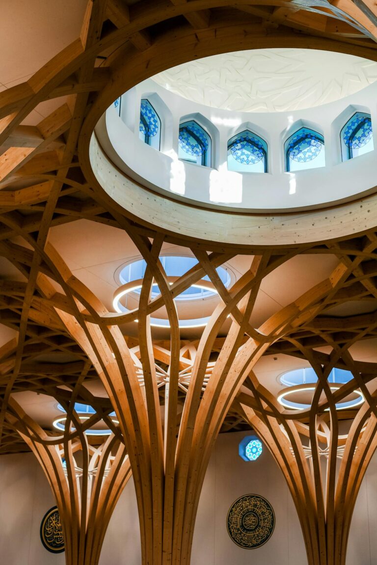 Interior view of Cambridge Mosque showcasing wooden arches and skylight.
